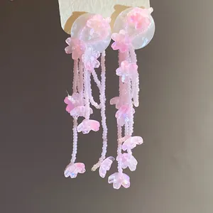 Pink resin flower tassel earrings with delicate beaded strands on white base.