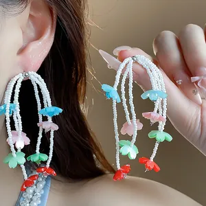 Detail view of colorful resin flower tassel earrings with white beads and vibrant petals