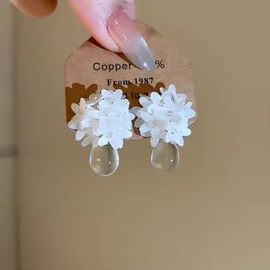Close-up of elegant French resin flower earrings with clear water-drop pendants