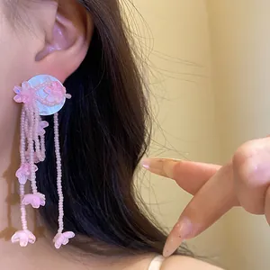 Close-up detail of a pink resin flower tassel earring worn by a model, showing style.