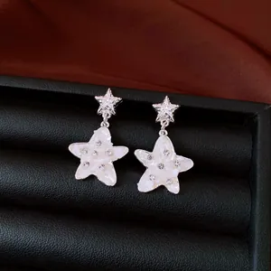 Close-up detail of silver star earrings featuring white mother-of-pearl and rhinestones