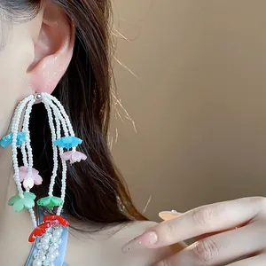 Detailed view of long tassel earrings with colorful resin flowers and white beading.