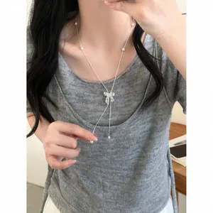 Detail of silver bow pendant necklace with zircons worn on model's neck