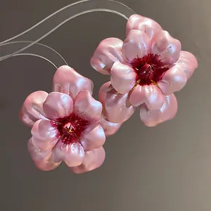 Detaillierte Makroansicht rosa metallischer Blumenohrstecker mit schimmerndem Perleffekt