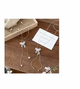 Detailed macro view of delicate lace bow lariat necklaces with pearls on wood