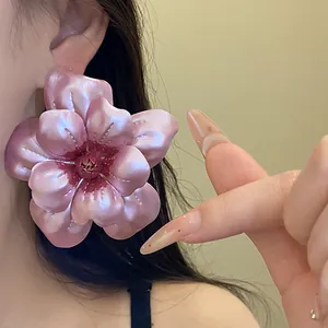 Nahaufnahme von eleganten rosa Metallblumen-Ohrringen mit Perlmutt-Lackierung