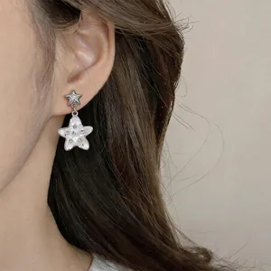 Detailed view of exquisite star earrings with mother-of-pearl and diamonds on ear