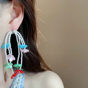 Close-up view of elegant white beaded tassel earrings featuring colorful resin flower accents