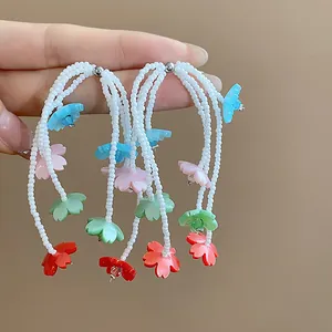 Hand holding colorful resin flower tassel earrings with delicate white beads detail