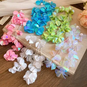 Dettaglio di orecchini colorati con nappe iridescenti e perle su libro vintage
