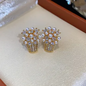 Dettaglio di eleganti orecchini a perno a cesto di fiori placcati oro 18k con perle e zirconi