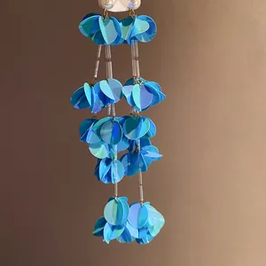 Primo piano di orecchini a nappa con paillettes blu a strati per stile retrò vacanza