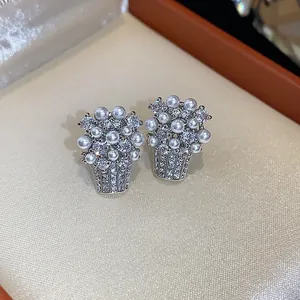 Primo piano di eleganti orecchini a lobo a cesto di fiori in argento con perle e CZ