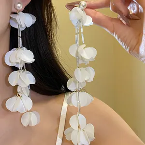 Dettaglio di orecchini a nappa lunga con petali di conchiglia bianca e perle indossati