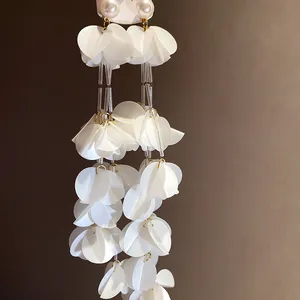 Primo piano di lunghi orecchini a nappa in conchiglia bianca con perle eleganti
