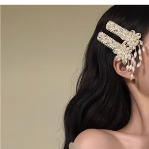 Macro view of elegant pearl flower hair clips with dangling tassels shown on model hair