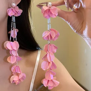 Dettaglio di orecchini vintage con nappe di petali di conchiglia rosa e perle, stile resort.