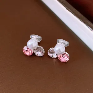 Dettaglio ravvicinato di eleganti orecchini a clip con strass rosa e perle bianche