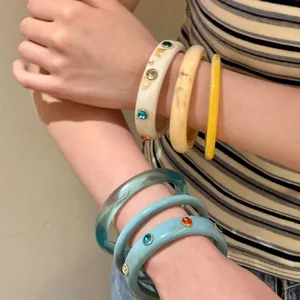 Primo piano di bracciali in resina colorata con strass scintillanti indossati al braccio