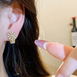 Dettaglio di un orecchino a perno a forma di cesto di fiori placcato in oro 18k con perle