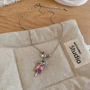 Vue détaillée d'un collier argenté avec pendentif esquimau en zircon rose et fleur.