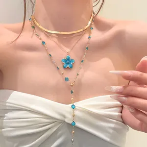 Elegant layered gold necklace set with blue enamel flower pendant on Asian model