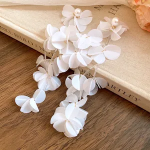 Dettaglio di orecchini lunghi a nappa in conchiglia bianca con eleganti perle chic.