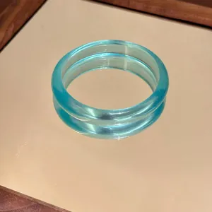 Dettaglio di un bracciale a cerchio blu acqua traslucido minimalista su superficie calda