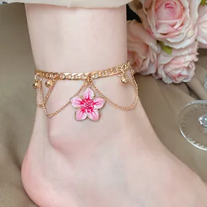 Detailed view of pink cherry blossom pendant on gold chain anklet worn on ankle