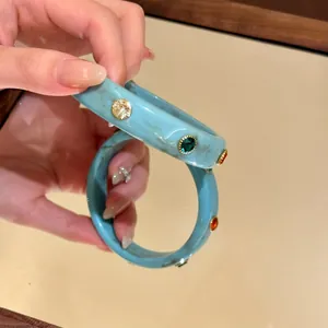 Vista dettagliata del bracciale rigido blu marmorizzato con cristalli colorati intarsiati