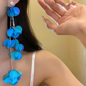 Dettaglio ravvicinato di eleganti orecchini a nappa blu con paillettes e perla