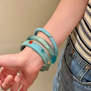 Set di tre eleganti braccialetti in resina turchese con strass colorati su un polso