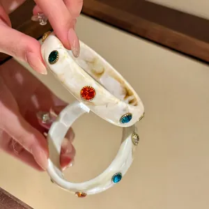 Vista dettagliata del bracciale rigido in resina marmorizzata bianca con strass colorati