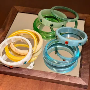 Gruppo di bracciali in resina colorata con strass incastonati su uno specchio.