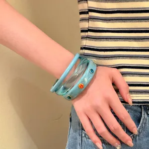 Dettaglio ravvicinato di tre eleganti bracciali rigidi blu chiaro con strass sul polso