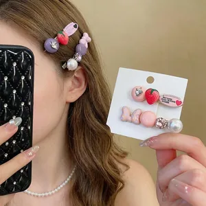 Elegant strawberry and pearl bow hair clips set with rhinestones on a display card