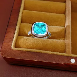 Primo piano di un lussuoso anello con zircone quadrato verde in un portagioie di legno.