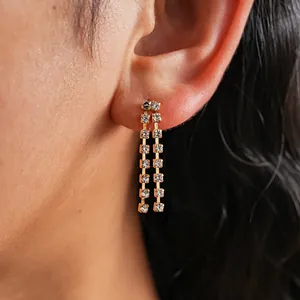 Close-up of golden tassel earrings with sparkling rhinestones on model