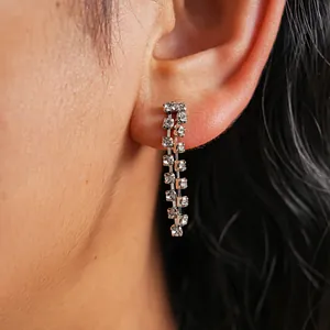 Close-up detail of elegant silver rhinestone tassel drop earrings worn on a model's ear