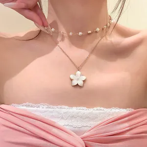 Detailed shot of a double-layered gold necklace featuring a sweet white flower pendant.