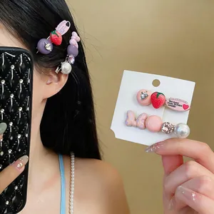 Close-up detail of strawberry and pink bow hair clips with pearls and rhinestones.
