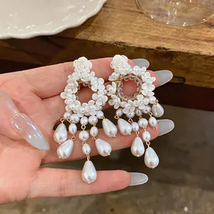 Primo piano dettagliato di eleganti orecchini francesi con fiori bianchi e nappe di perle