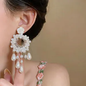 Primo piano dettagliato di orecchini floreali stile francese con nappe di perle su modella