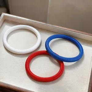 Trois bracelets à ressort minimalistes élégants en blanc, rouge et bleu sur un présentoir