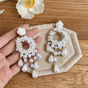 Dettaglio degli orecchini francesi con nappe di perle e fiori, perno a rosa bianca.
