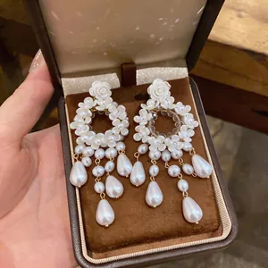 Eleganti orecchini a fiori bianchi stile francese con nappe di perle in confezione.