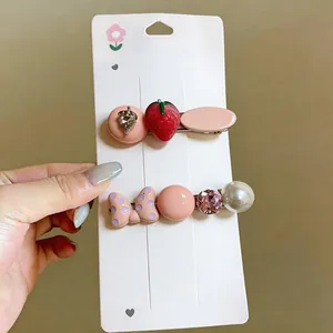 Detailed view of cute strawberry and pearl hair clips with polka dot bow accent on card