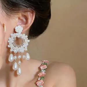 Primo piano di eleganti orecchini a fiore e perla con nappa alla francese
