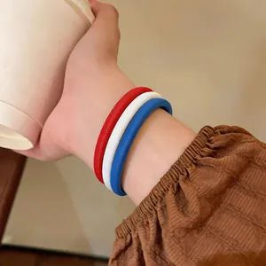Gros plan de trois bracelets à ressort colorés rouge, blanc et bleu sur un poignet