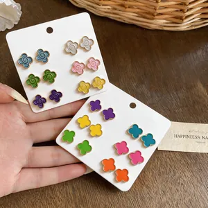 Detailed macro view of colorful camellia and four-leaf clover flower stud earrings on cards